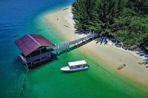 An aerial view of a beachside property with a dock, a boat, and a wooden walkway leading to a building. - Ara Dinawan Island Resort (Kinarut)