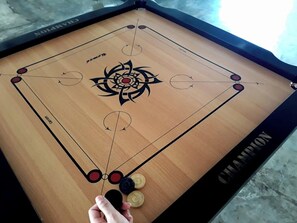 A foosball table with a 'CHAMPION' label and a hand holding a ball. - Ara Dinawan Island (Kinarut)