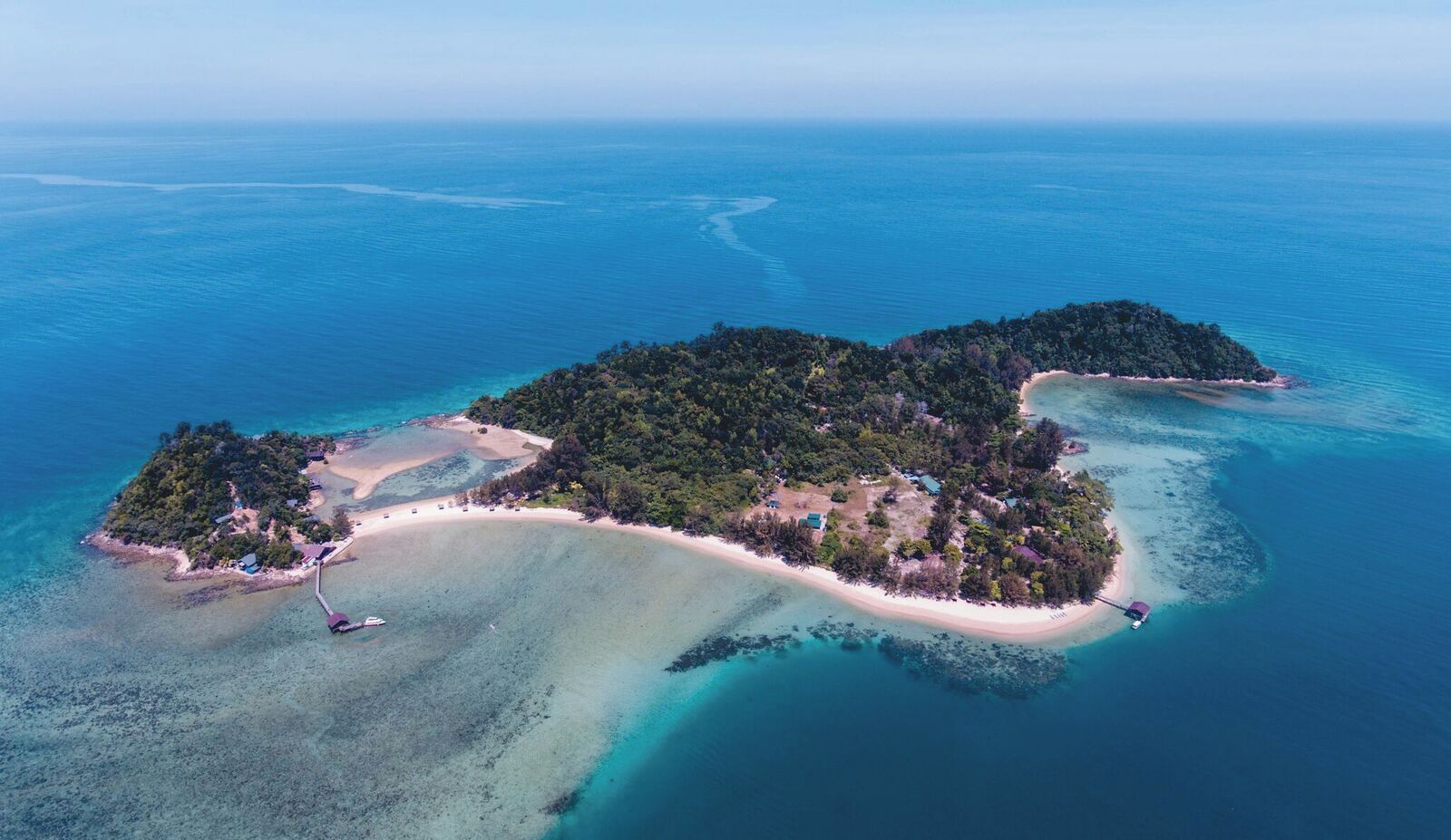 Une vue aérienne d’une île tropicale, avec ses eaux turquoise limpides, ses plages de sable et sa végétation luxuriante.