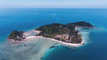 Une vue aérienne d’une île tropicale, avec ses eaux turquoise limpides, ses plages de sable et sa végétation luxuriante.