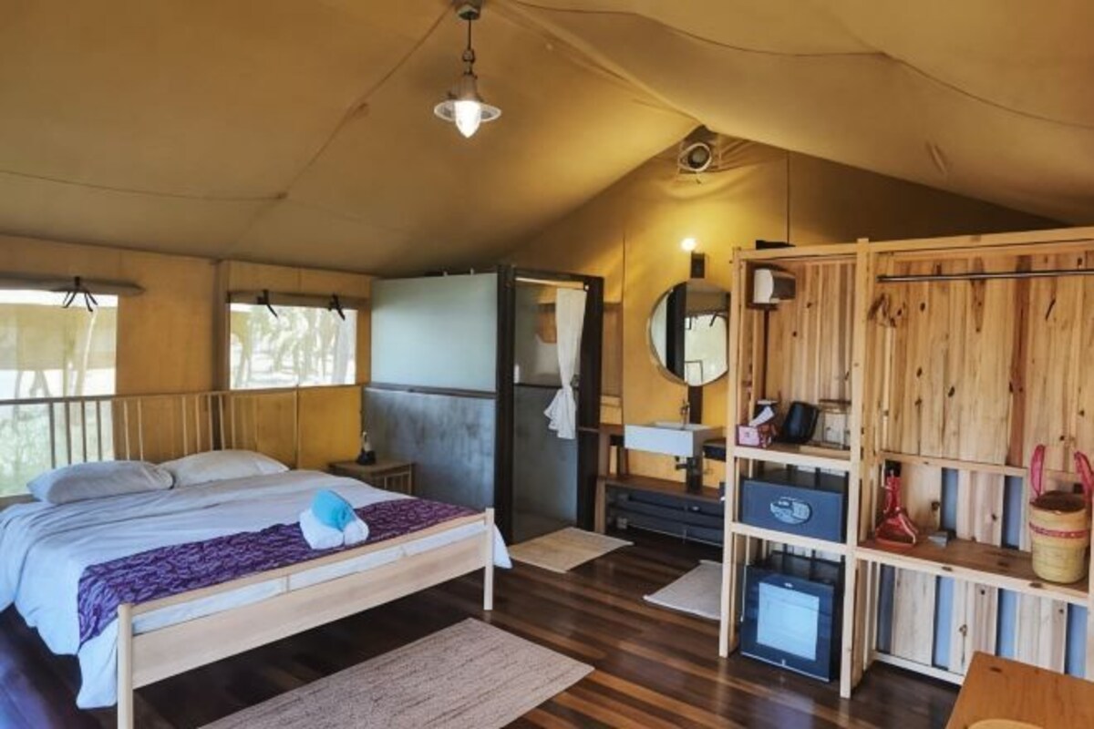 A bedroom with a bed, bedside table, mirror, wardrobe, and a small desk with a chair.