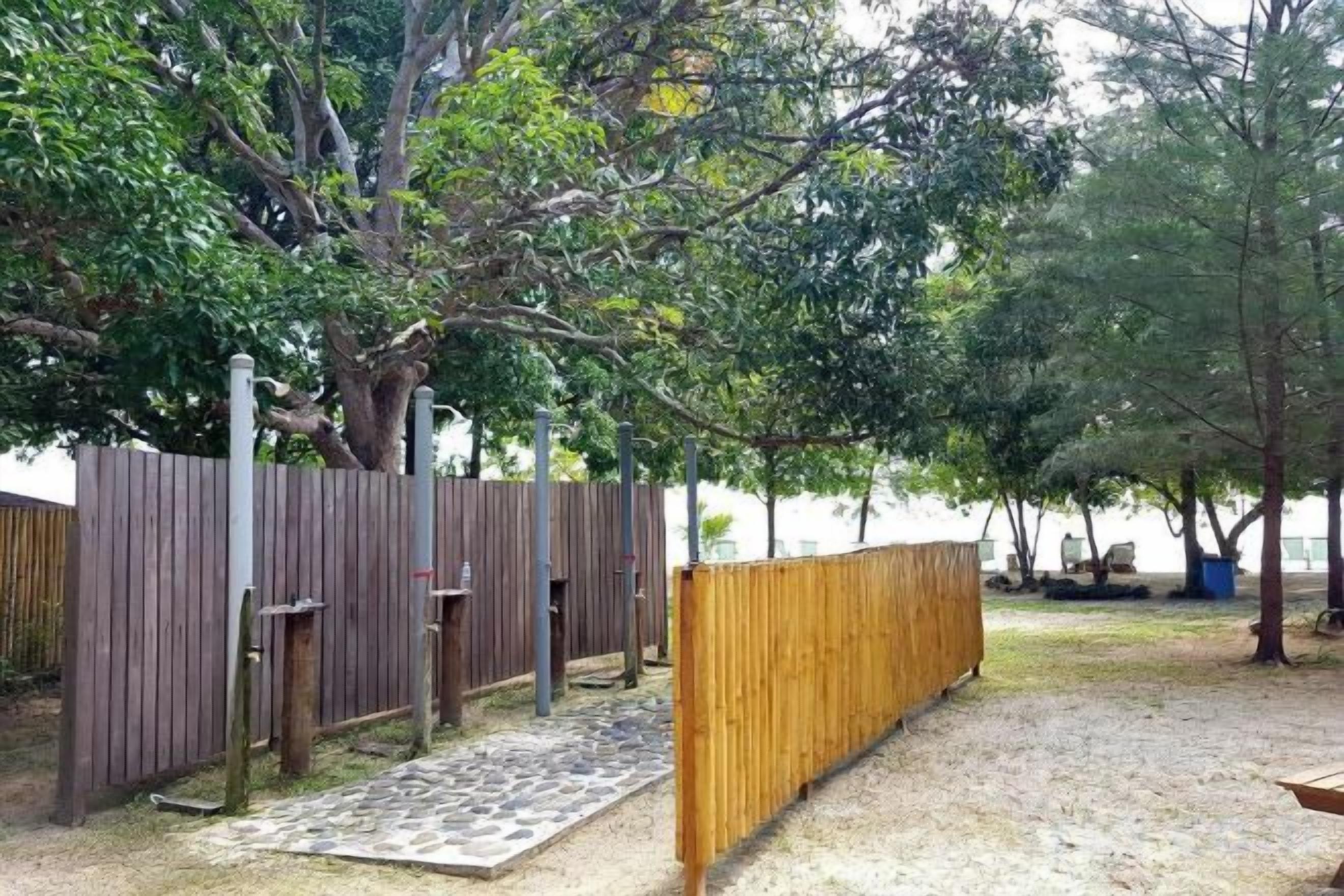 A fenced outdoor area with a wooden bench and a paved walkway.
