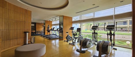 Un gimnasio con máquinas de cardio, pesas y un muro de espejos.