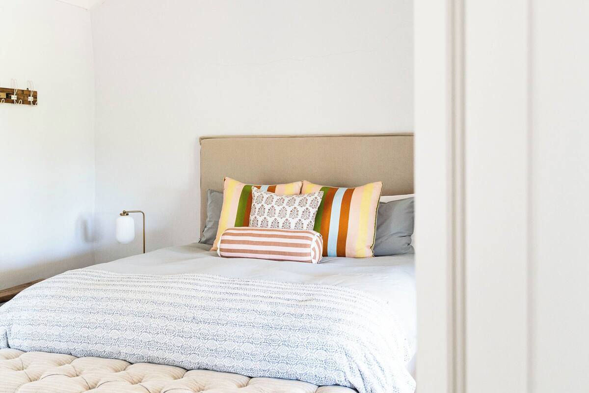 A bedroom with a bed, a bench, a nightstand, and a ceiling light.