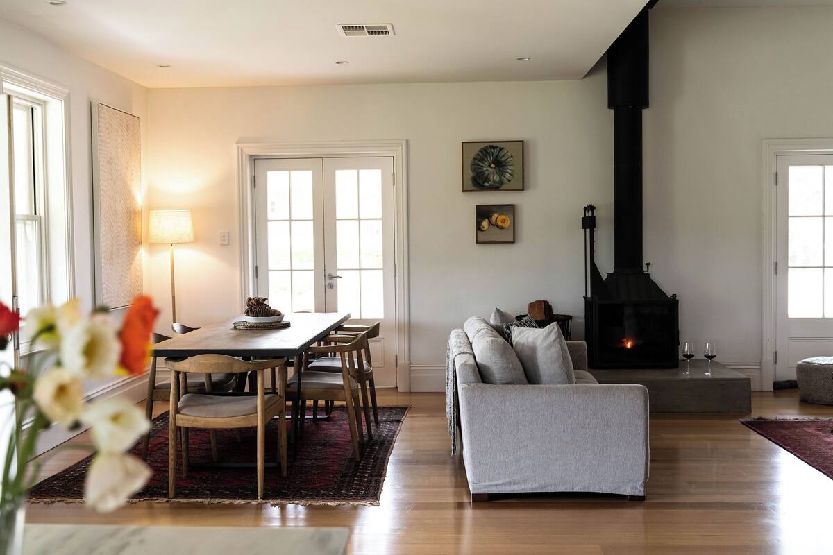 A modern living room with a fireplace, a dining area with a table and chairs, and a sofa.