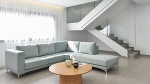 A modern living room with a light grey sectional sofa, a wooden coffee table, and a glass staircase with a white railing. - Villa in Salobre With Pool & Golf Nearby (San Bartolomé de Tirajana)