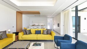 A modern living room with a yellow sofa, blue chairs, and a marble coffee table. - Villa in Salobre With Pool & Golf Nearby (San Bartolomé de Tirajana)
