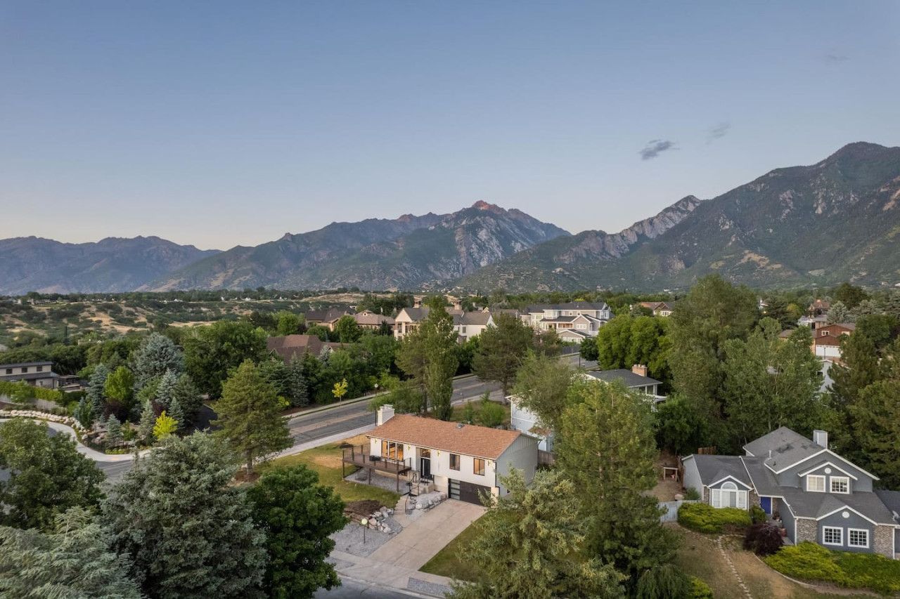 A residential area with houses, trees, and mountains in the background.