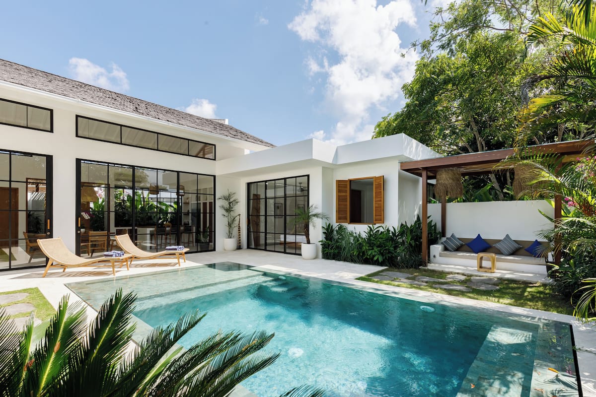 A modern house with a swimming pool, large windows, and outdoor seating.