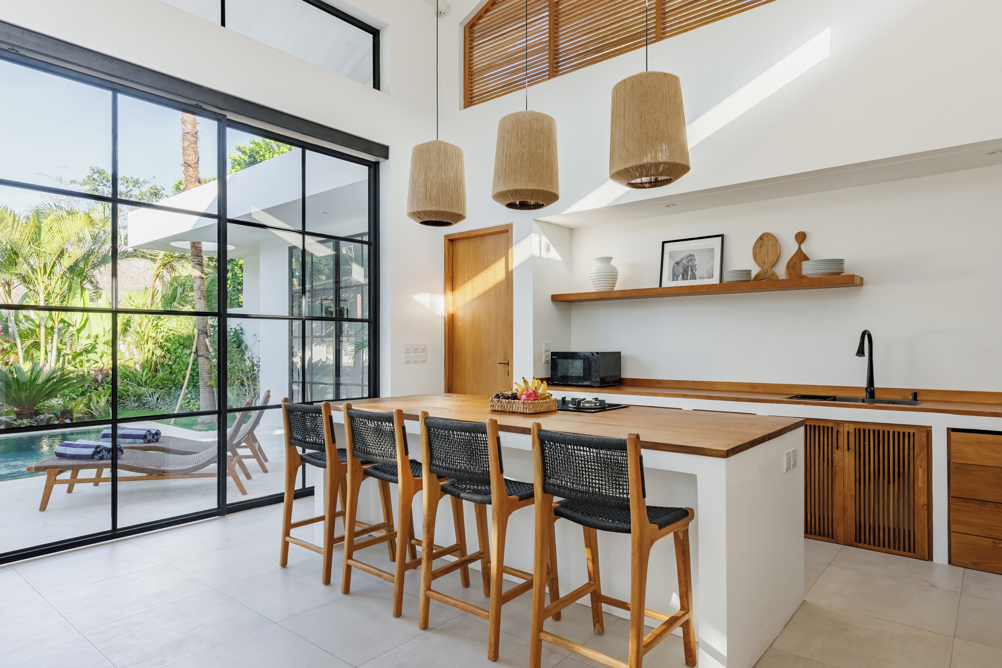A modern kitchen with a large island, bar stools, and a view of a pool.