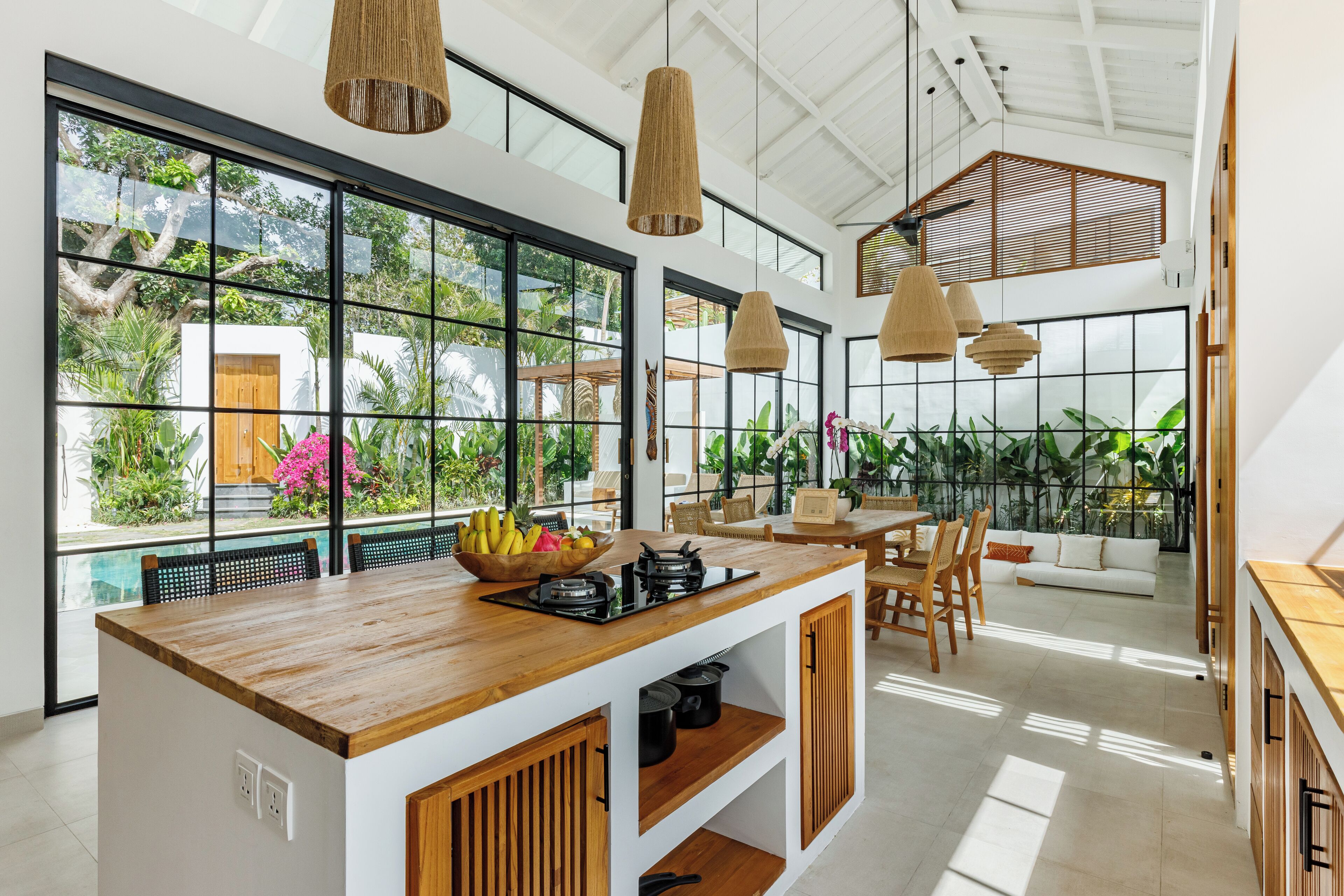 A spacious kitchen with a wooden island, large windows, and hanging pendant lights.
