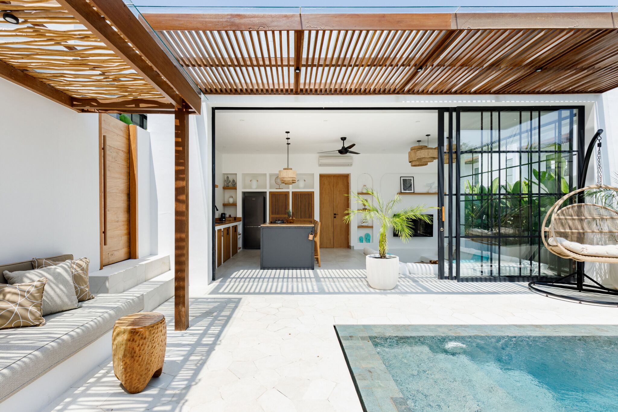 Un área exterior moderna con piscina, pérgola de madera y una zona de estar acogedora.
