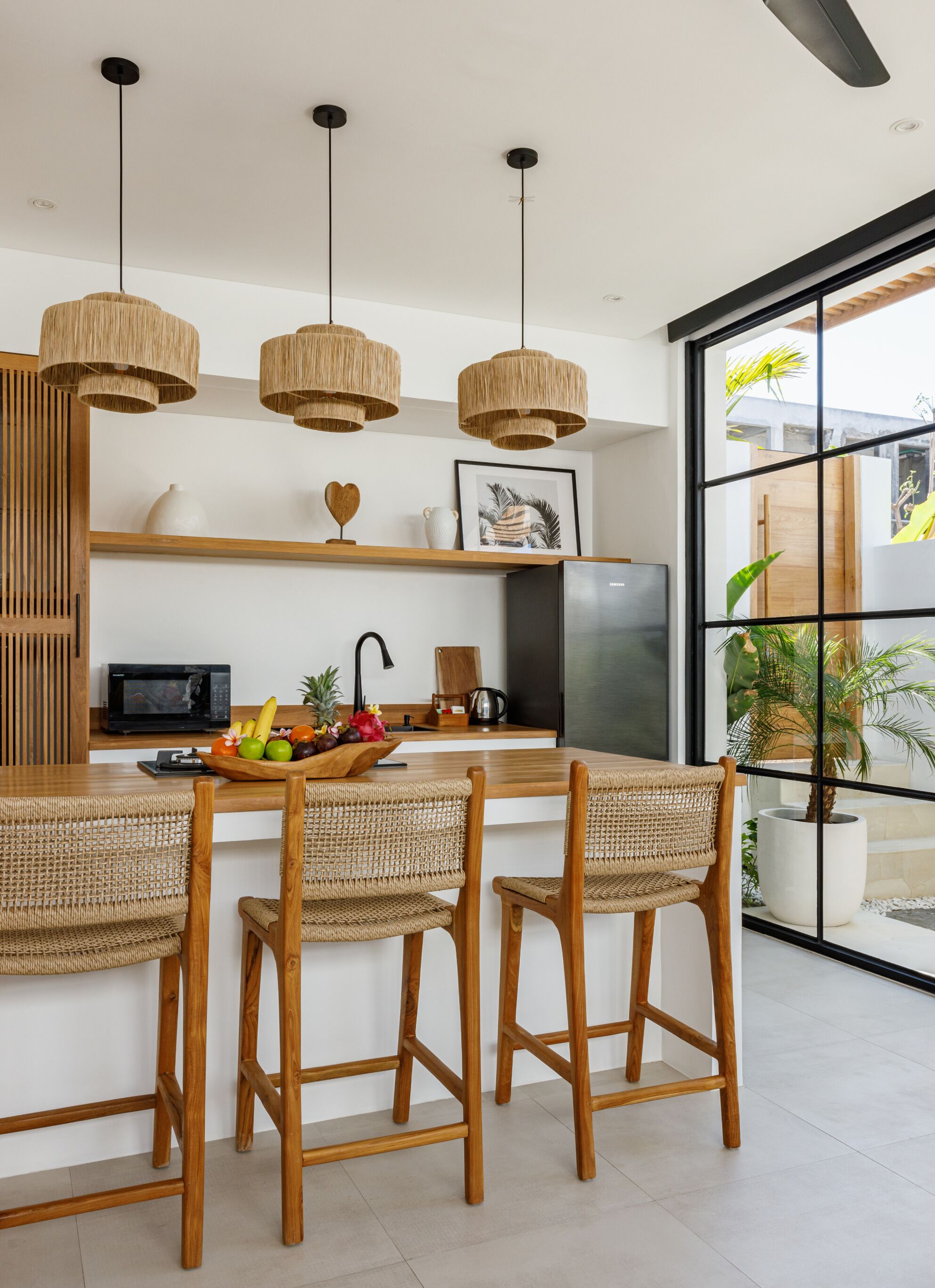 Una cocina moderna con una isla central, sillas de madera y un ventanal con vistas a zonas verdes.