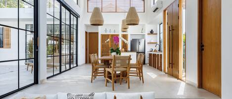 A spacious, well-lit interior with a dining area, large windows, and a modern kitchen.