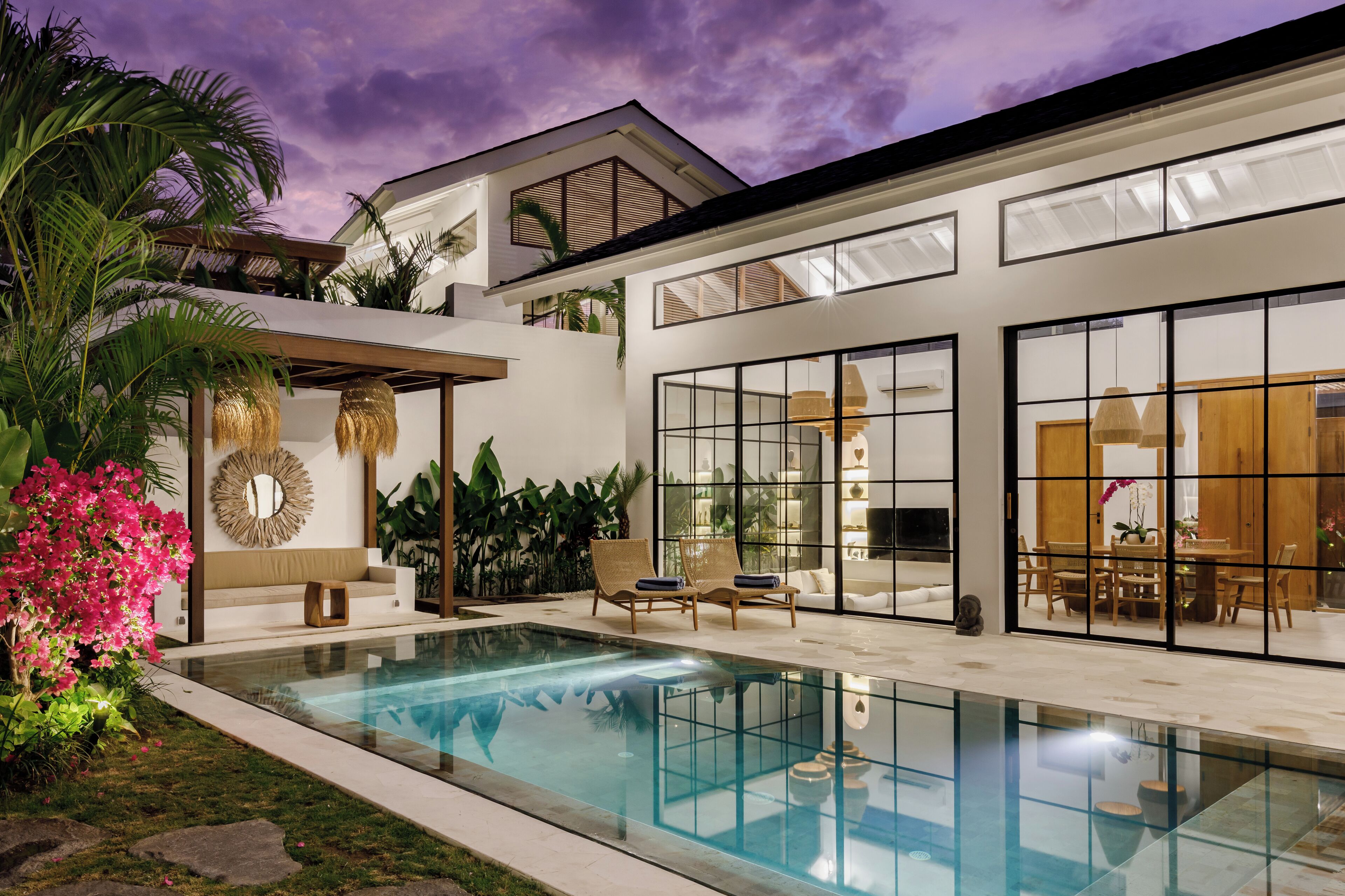A modern house with a swimming pool, large windows, and outdoor furniture.