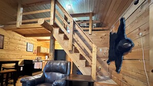 A wooden interior with a staircase, a leather chair, and a mounted animal head. - Rustic and cozy cabin with all new amenities near beautiful Hatcher’s Pass (Palmer)