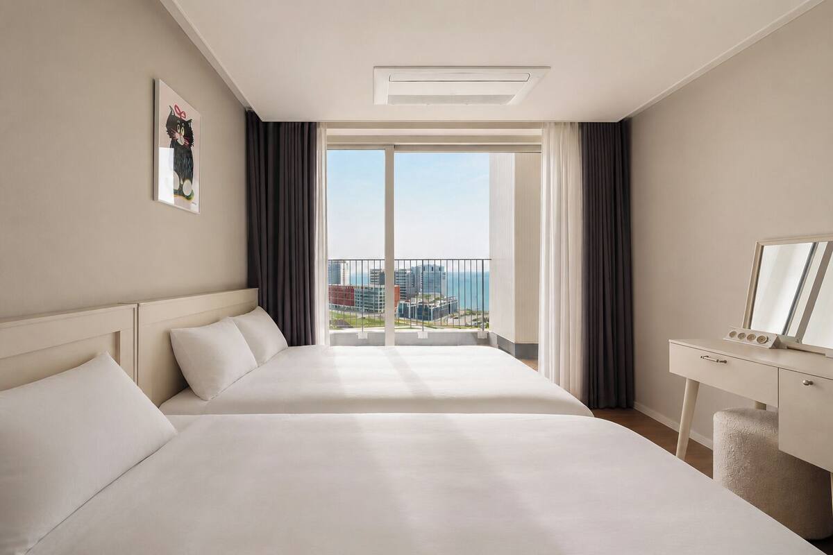 A hotel room with a large bed, a desk with a mirror, and a view of the cityscape.