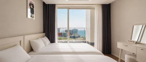 A hotel room with a large bed, a desk with a mirror, and a view of the cityscape.