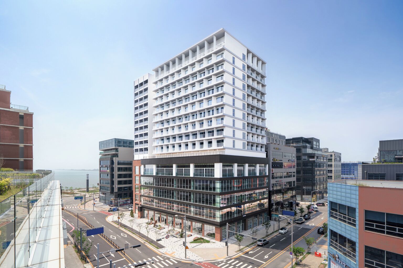 A modern hotel with multiple floors, large windows, and a view of the sea.