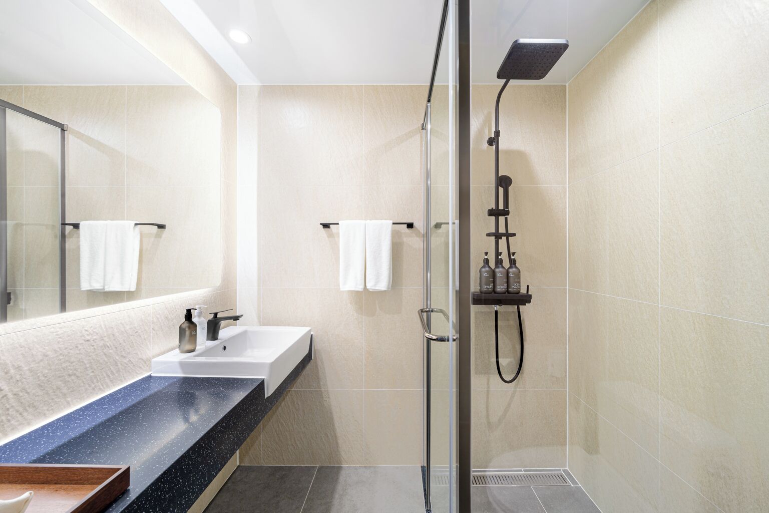 Une salle de bain moderne avec une douche à parois de verre, un lavabo doté d’un plan de travail en marbre et un grand miroir.