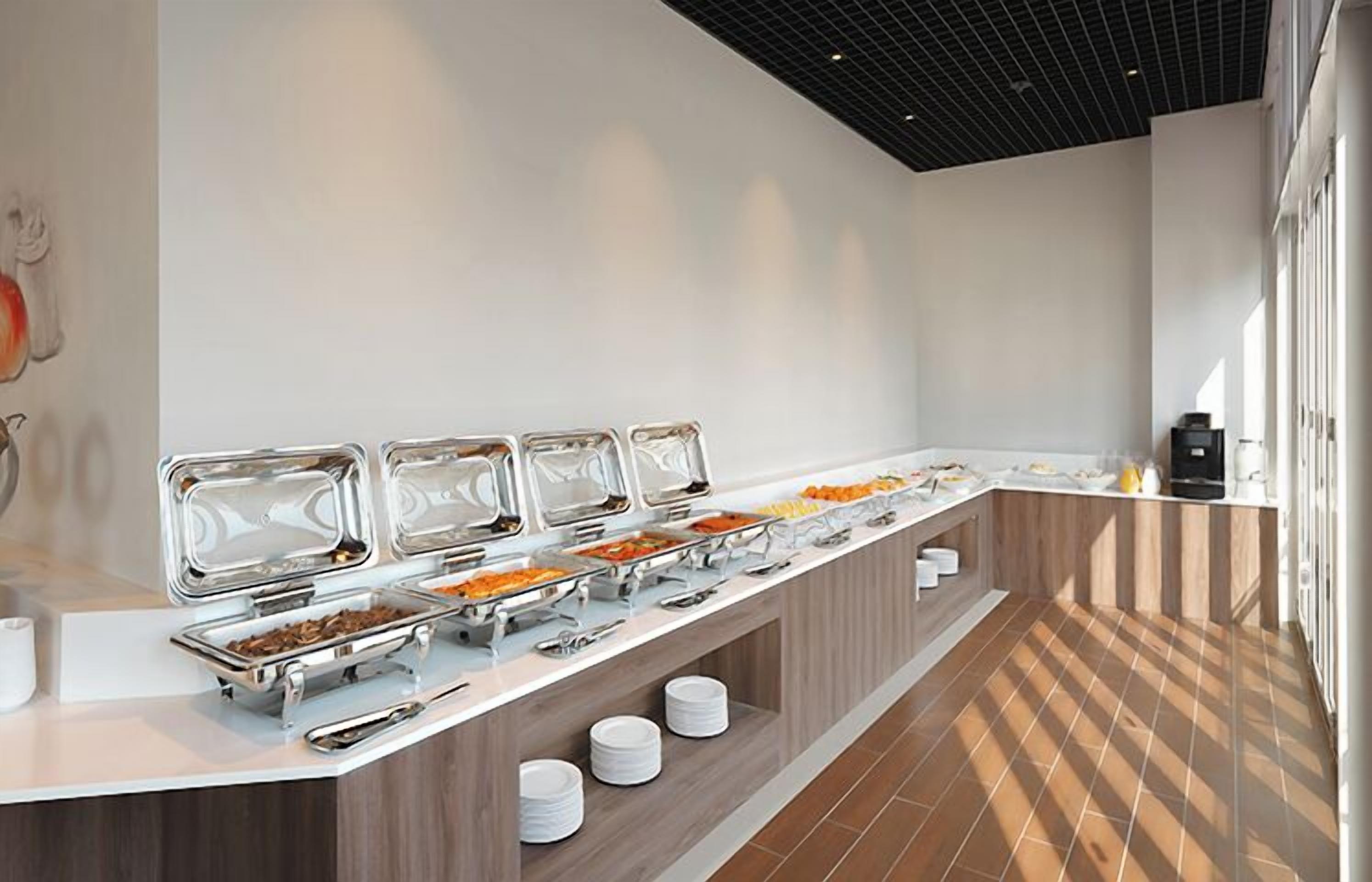 A buffet setup with multiple food stations, a white counter, and a tiled floor.