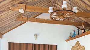 Un salon chaleureux avec un plafond en bois, un canapé en cuir noir, une table basse en bois et une grande porte en bois.
