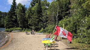 Une plage avec un drapeau canadien, des chaises de plage et une table.