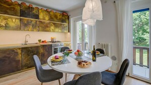 A modern kitchen with a dining area, a large window with curtains, and a view of greenery outside. - Studio Paradiso - Ski In Ski Out 300m, Sestriere, Italy (Sestriere)