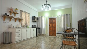 A compact kitchen with white cabinets, a microwave, and a small dining area with a metal table and chairs. - Secret Place  (Gros islet)