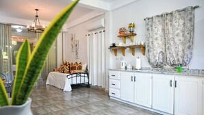 A modern kitchen with white cabinets, a dining area with a table and chairs, and a living room with a sofa and a plant. - Secret Place  (Gros islet)