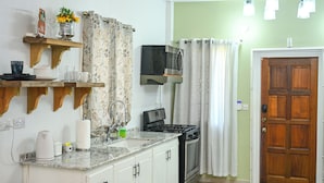 A kitchen with a stove, microwave, and a wooden door. - Secret Place  (Gros islet)