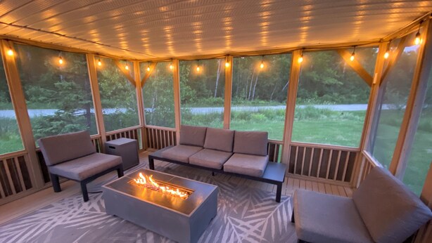Une terrasse extérieure dotée d’un foyer, de sièges et de guirlandes lumineuses.