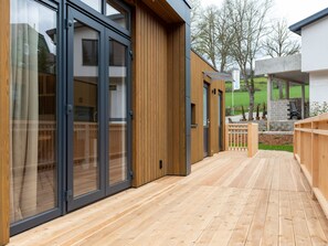A modern building with large glass doors, a wooden deck, and a view of a green landscape. - Modern Chalet With Dishwasher, in a Holiday Park, in a Natural Environment (Parc Hosingen)