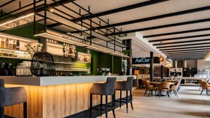 A modern bar area with a wooden counter, black bar stools, and a green accent wall. - Modern Chalet With Dishwasher, in a Holiday Park, in a Natural Environment (Parc Hosingen)