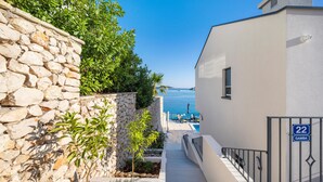 A narrow stone pathway leading to a modern building with a pool and a view of the sea. - Gorgeous home in Sevid (Sevid)