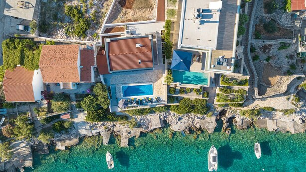An aerial view of a coastal property with a swimming pool, multiple boats, and a rocky shoreline. - Gorgeous home in Sevid (Sevid)
