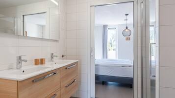 A modern bathroom with a double sink, wooden vanity, and a large mirror.