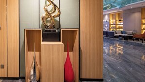 Un hall d’entrée moderne doté d’un plafond en verre, de lambris en bois et d’une sculpture décorative centrale.