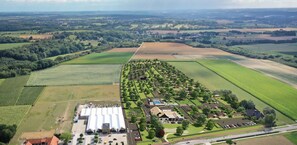 An aerial view of a residential area with a large building complex, green fields, and scattered houses. - Nice Chalet With Terrace, 9 km From Maastricht (Berg en Terblijt)