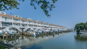 Un port de plaisance avec des bateaux amarrés et une rangée d’immeubles à plusieurs étages dotés de balcons.