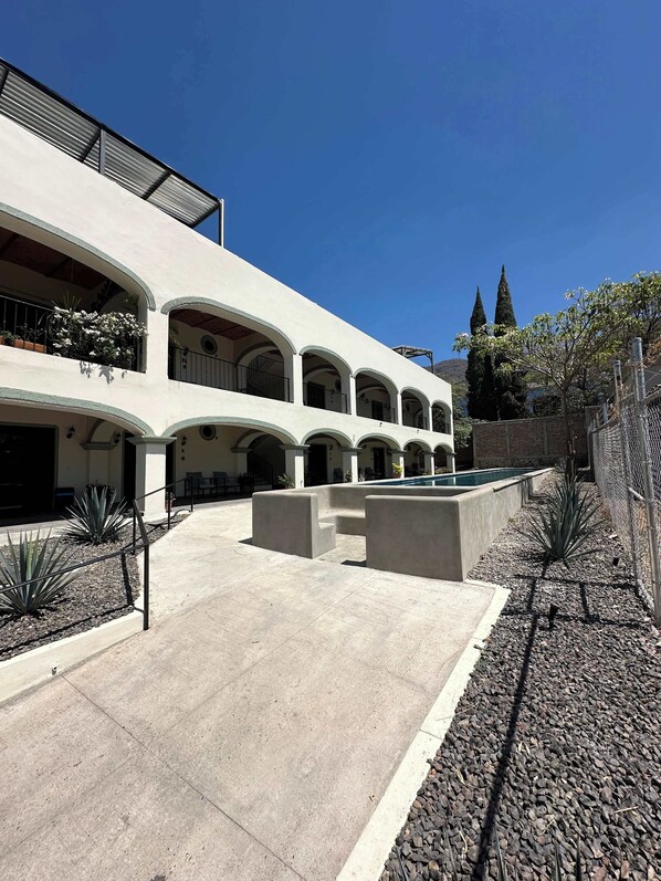 Un edificio de varios niveles con un patio central, mobiliario exterior y una piscina.