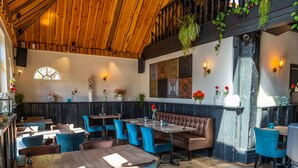 A restaurant interior with wooden ceiling beams, blue upholstered chairs, and a central seating area with a cushioned bench. - Nice Chalet on a Holiday Park 25 km From Amsterdam (Velsen-Zuid)