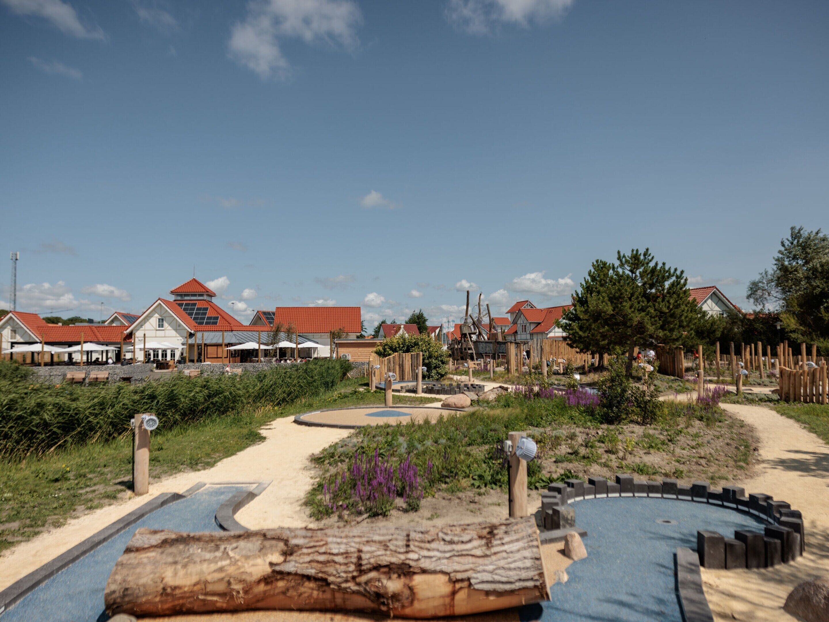 Een kustresort met rode daken, een zandstrand en een houten omheining.