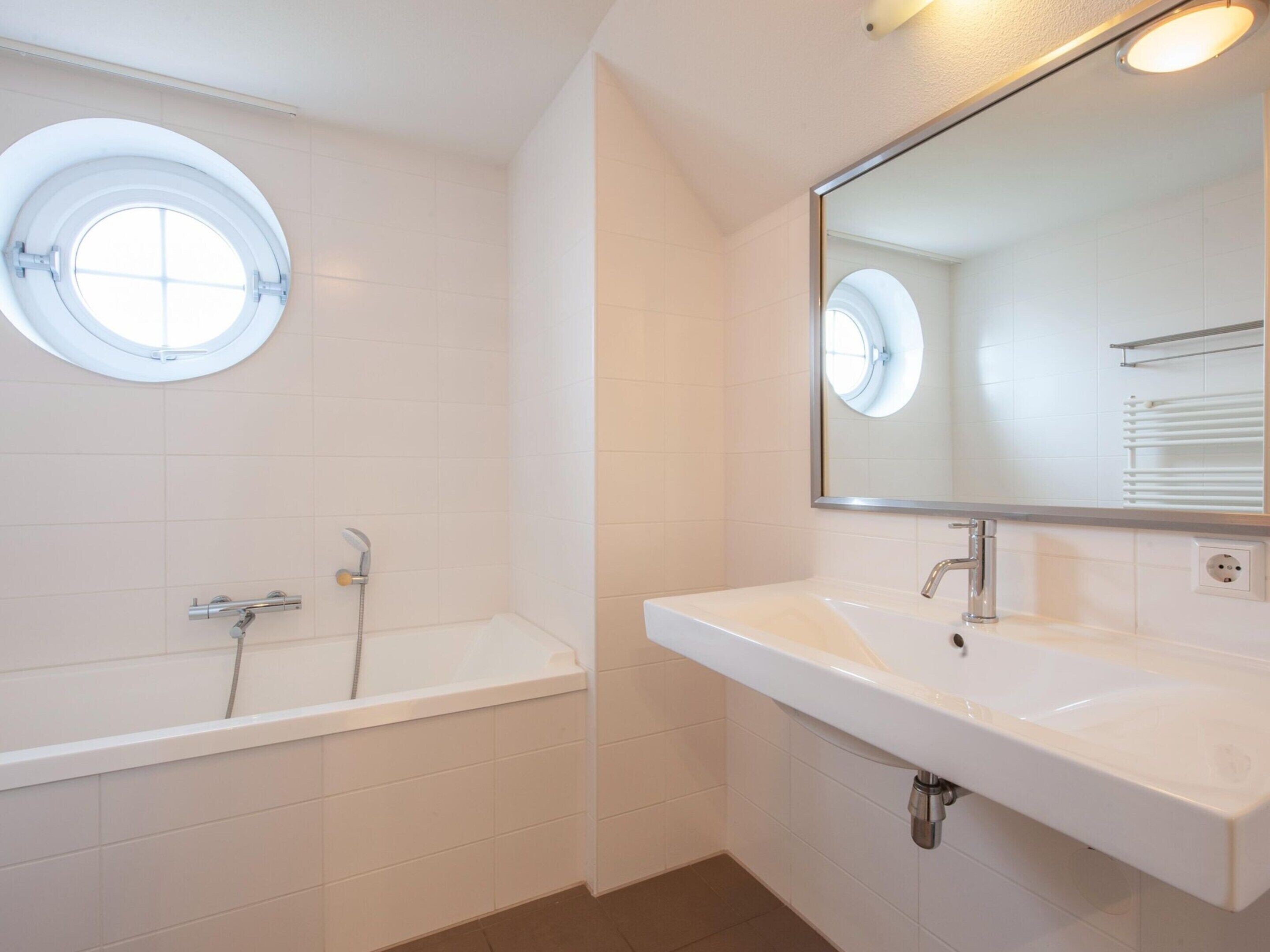 A modern bathroom with a bathtub, a sink, and a large mirror.