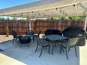 An outdoor patio with a covered seating area, a table, and a grill. - Historic Atascadero Colony Charmer! (Atascadero)
