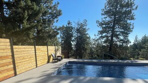 Una piscina con cubierta de madera, barandilla metálica y un banco rojo.