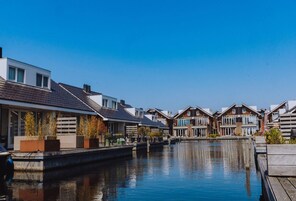 A canal-side residential area with modern houses, a wooden dock, and a calm water body.