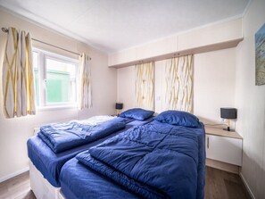 A bedroom with a bed, two bedside tables, a window with curtains, and a painting on the wall. - Veluwemeer Chalet With Microwave (Nunspeet)