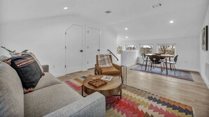 A spacious living room with a sofa, a coffee table, and a dining area with a table and chairs. - Modern Eastside Home with Gourmet Kitchen, 3 Floors, Game Room, Walk to restaurants and bars (Austin)