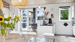 Cocina moderna con comedor, que incluye un juego de mesa, un jarrón con girasoles y vistas al exterior.